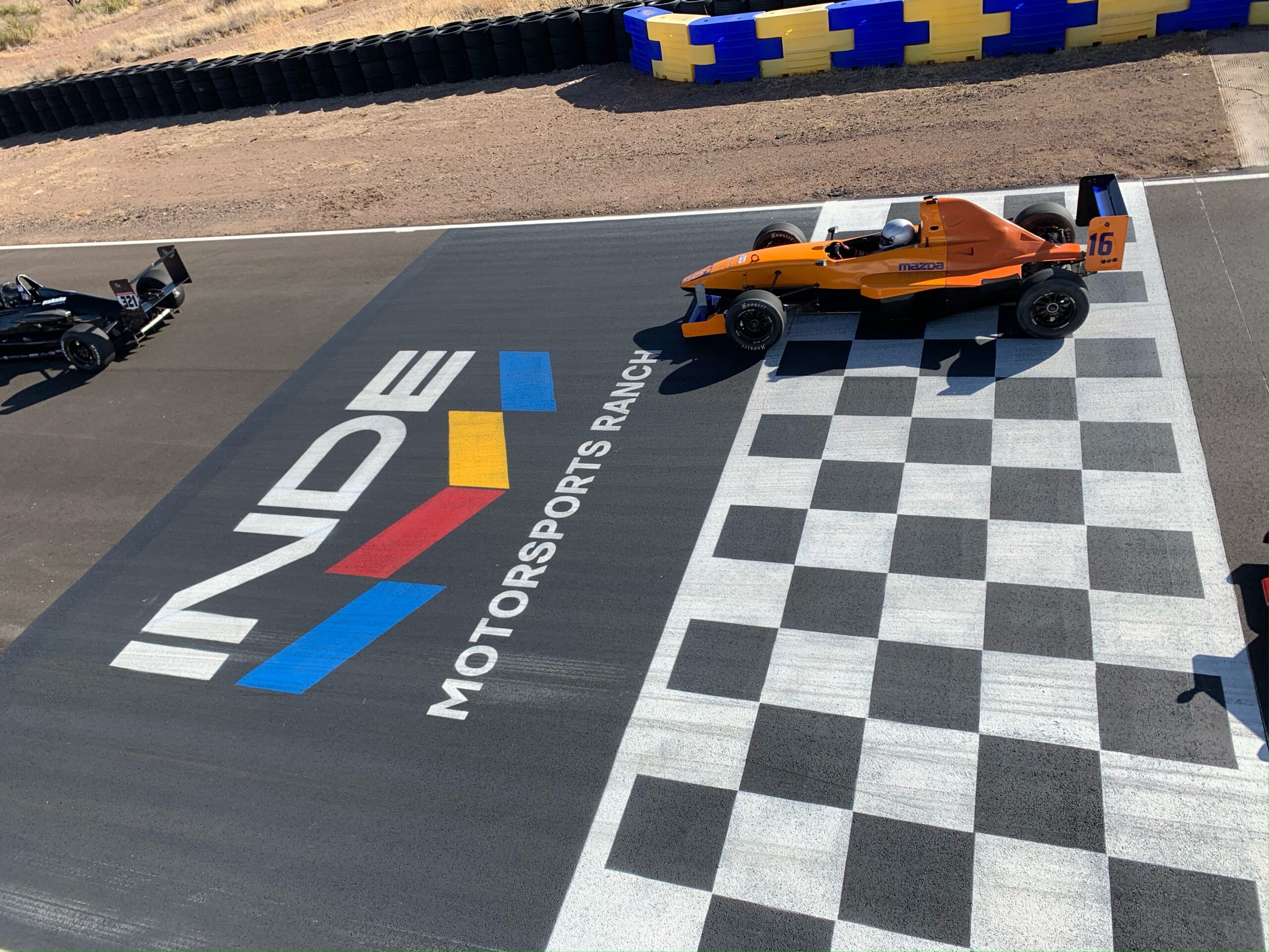 Race cars crossing the INDE Motorsports Ranch finish line