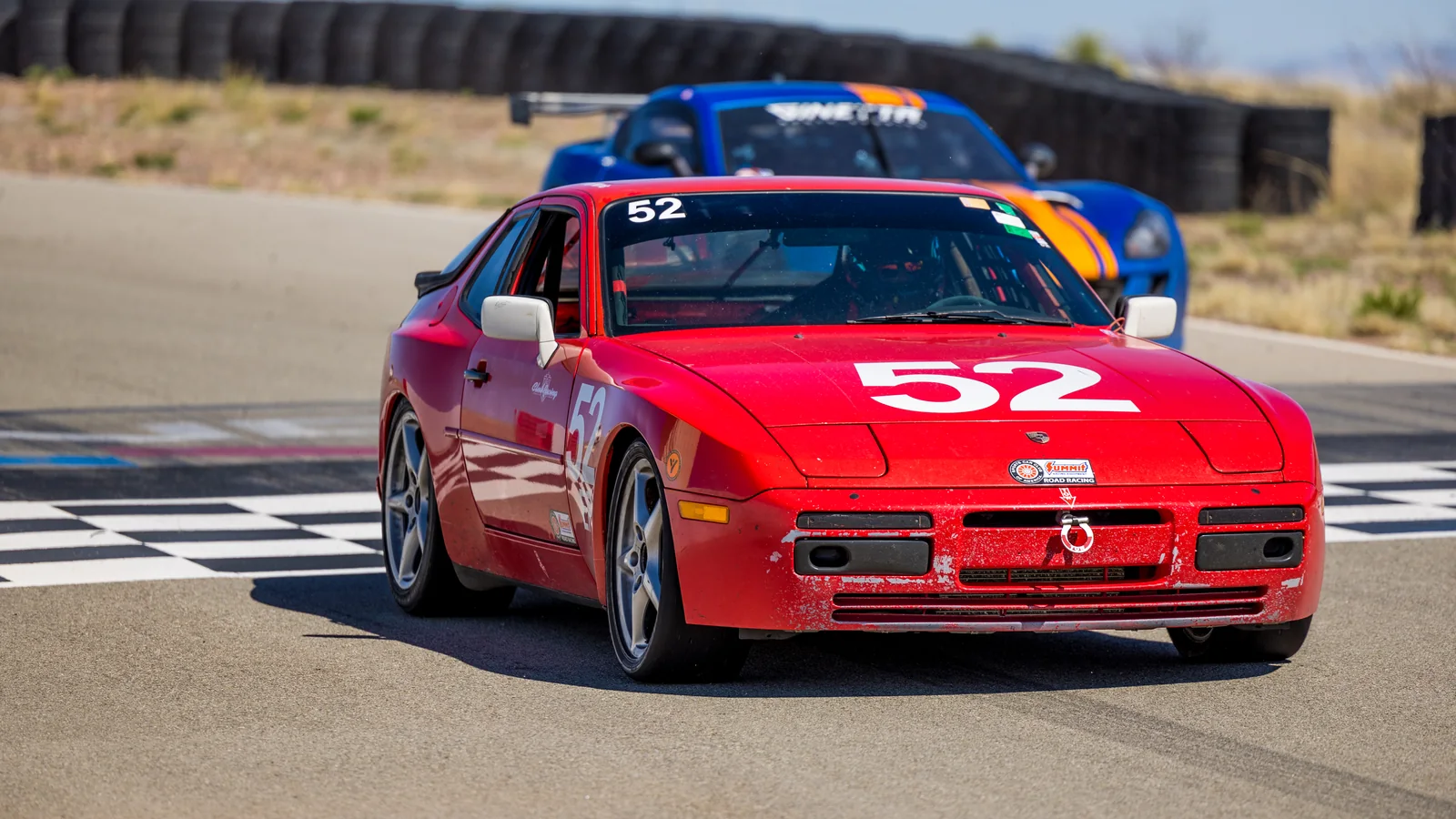 Red number 52 Porsche crossing the checkered finish line