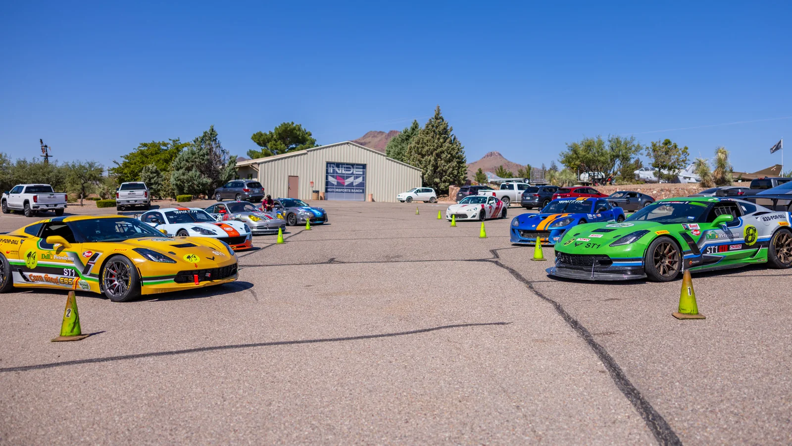 Colorful race cars lined up in the INDE Motorsports Ranch paddock
