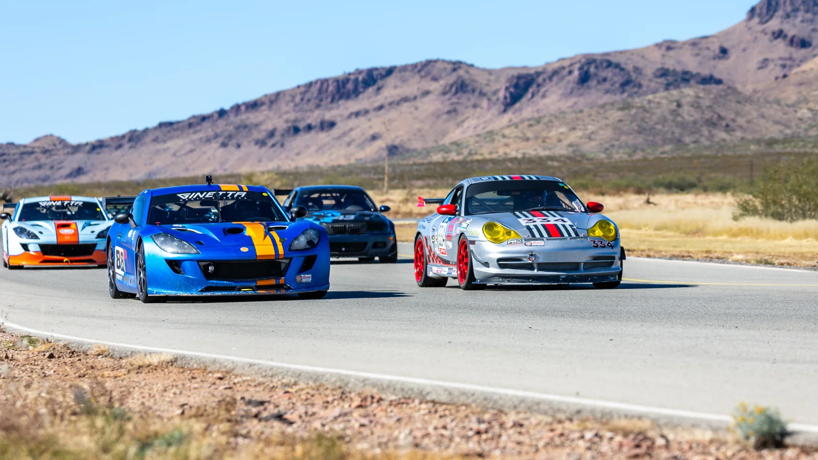 Blue Ginetta and silver Porsche racing side by side at INDE